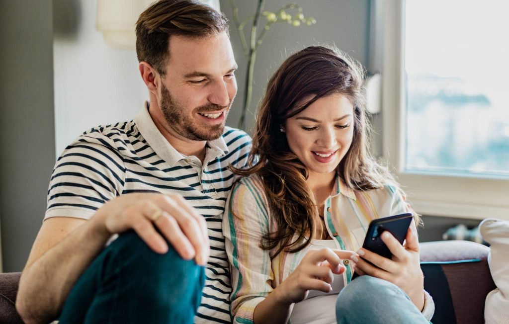 Couple using smart phone at home