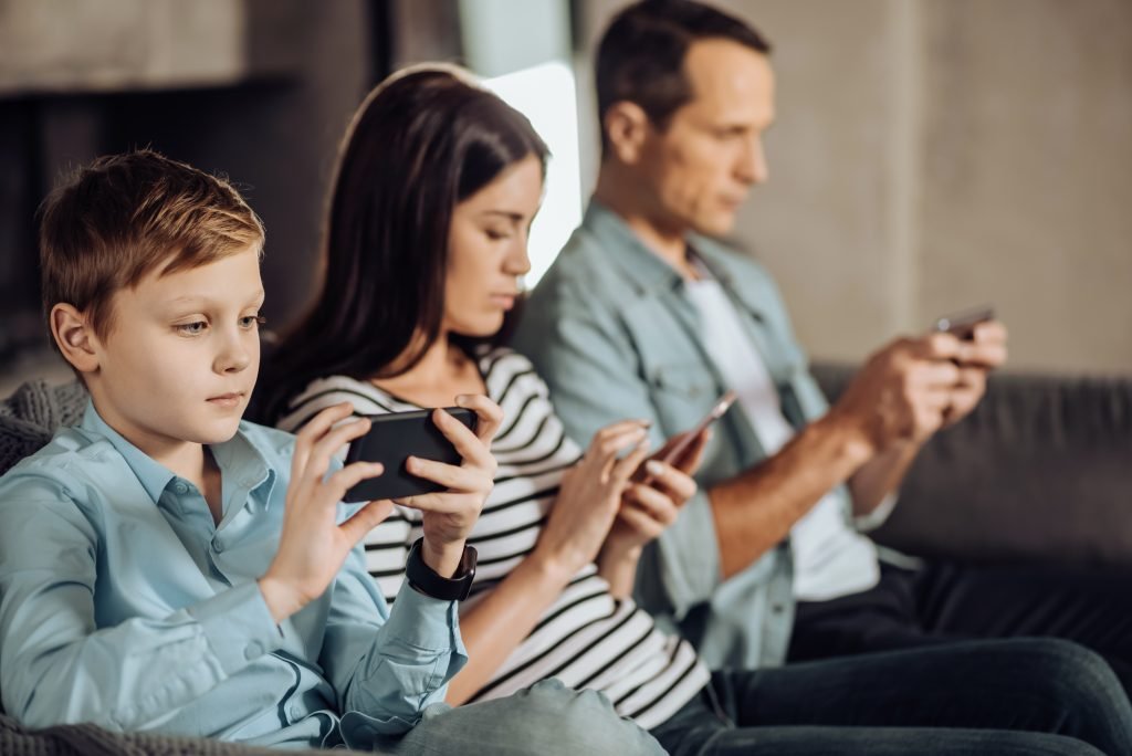 Little boy and his parents using their phones