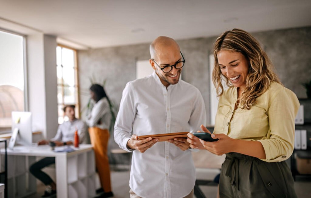 Businessman and businesswoman smiling looking at phone